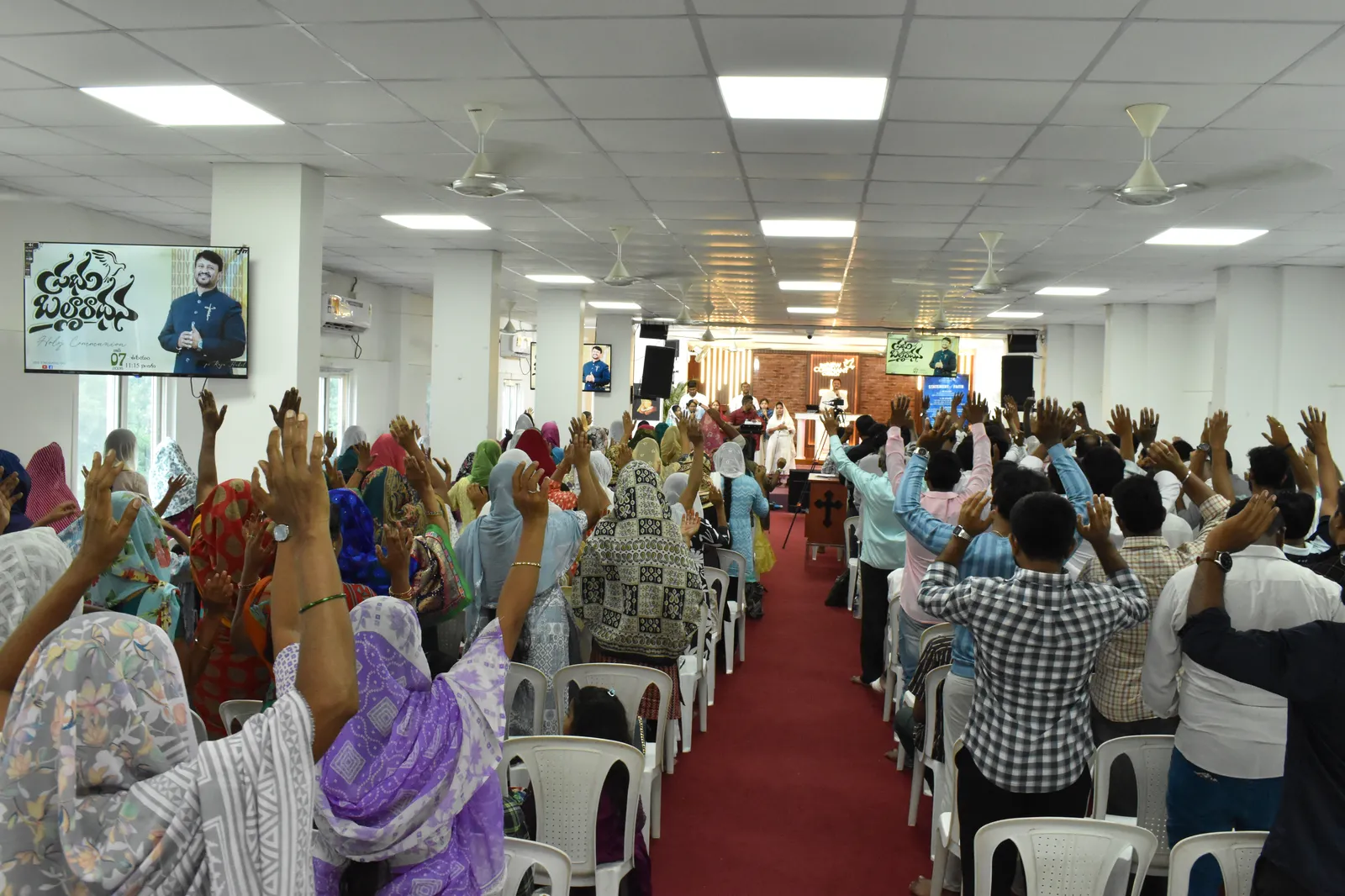 The New Covenant Church congregation raising hands in worship